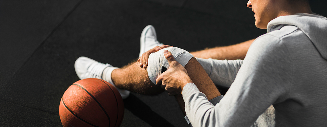 basketball player applying bandage knee